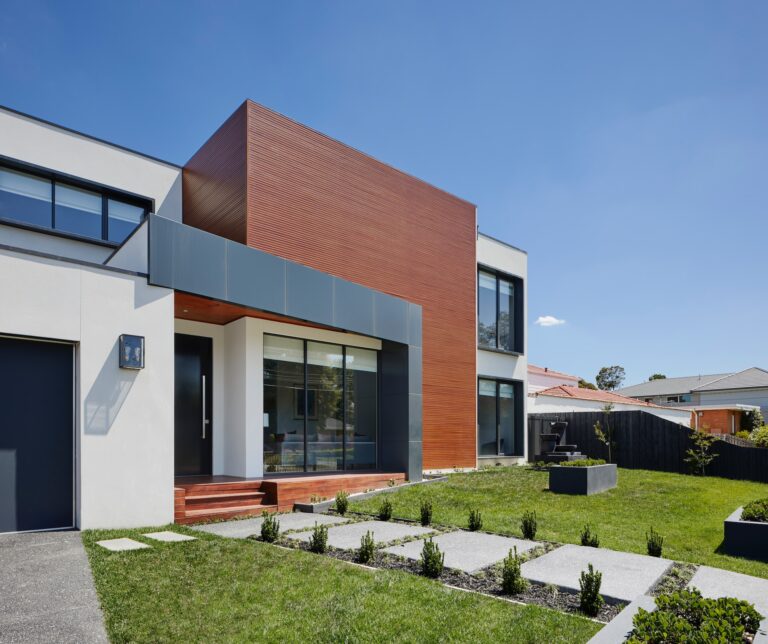 een modern huis met een groen gazon en landschapsarchitectuur.