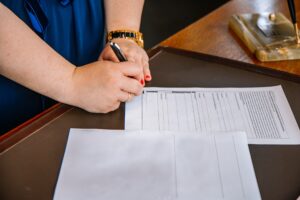 een persoon die aan een tafel zit met pen en papier.