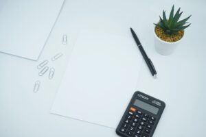 een rekenmachine, pen en papier op een tafel.