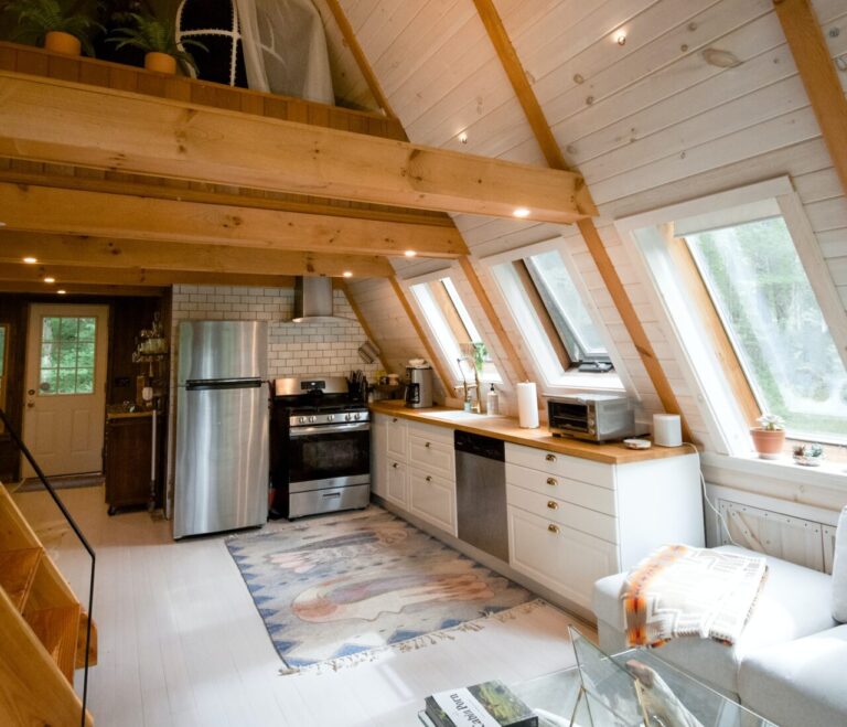 een keuken op een zolder met een kookplaatoven onder een raam.